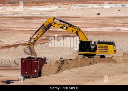 A heavy duty excavator loads a container truck with hazardous uranium tailings at the UMTRA remediation project, Moab, Utah. Stock Photo