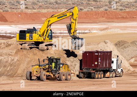 A heavy duty excavator loads a container truck with hazardous uranium tailings at the UMTRA remediation project, Moab, Utah. Stock Photo