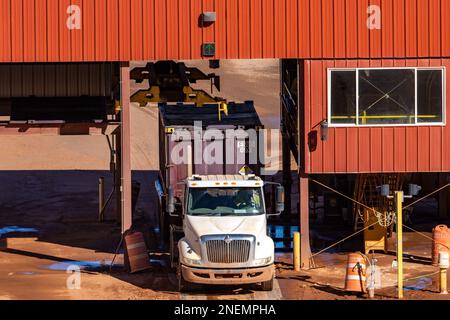 An empty container truck having its container cap removed at the UMTRA tailings project in Moab, Utah.  The hoist is sliding over the container to rem Stock Photo