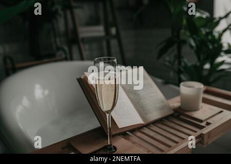 Native hues organic shapes look of bathroom with big window oval bathtub in neutrals earth tones. Green palm plants candles bubblebath leasure and rel Stock Photo