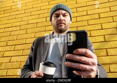 Man in black knit cap and black knit cap holding white analog wall