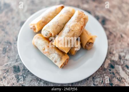 Fried spring egg rolls on white plate macro closeup above view in chinese asian restaurant or home as appetizer for dinner Stock Photo