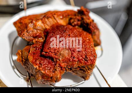 Roasted chuck roast cooked brown meat on white plate macro closeup cooling on rack as pile of tender meat Stock Photo