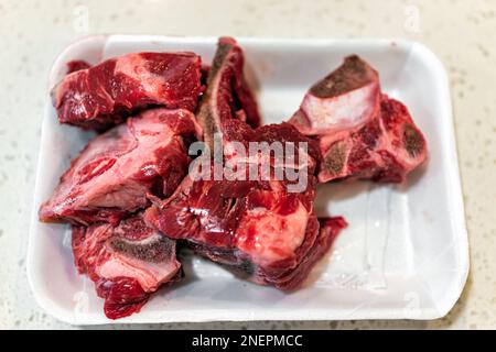 Flat top above view closeup of beef knuckle red raw bones on butcher tray with uncooked meat on table for cooking Stock Photo