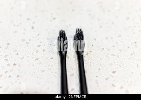 Closeup macro of pair of two toothbrushes in black plastic and bristles infused with charcoal whitening ingredient Stock Photo