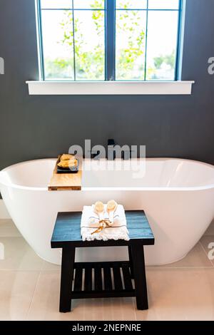 Bathtub in bathroom staging model home house room or hotel with modern luxury white cabinets interior, window with light and mirrors Stock Photo