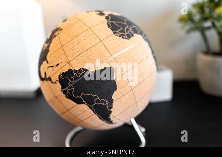 Modern or vintage retro brown globe world map with equator and South America continent as home office decoration and plant in background Stock Photo