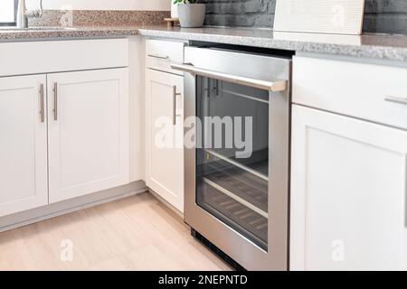 Modern white kitchen cabinets and mini bar appliance by granite countertop, tile backsplash by window in contemporary staging model home house or apar Stock Photo