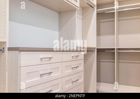 Spacious walk-in closet shelves, chest of drawers in modern minimalist white style in staging model house apartment bedroom Stock Photo