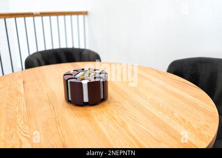 Gram Texas Hold 'em poker chip set with striped dice chips and two decks of cards carousel on wooden table with chairs in game room of staging model h Stock Photo