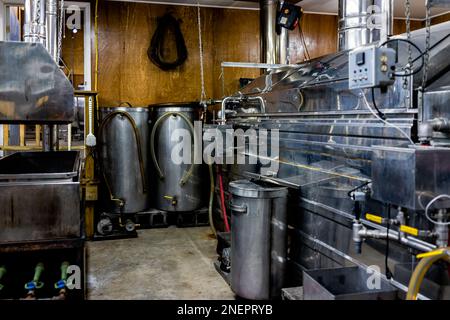 Maple syrup industrial machines that collect sap with tubes connected to trees for production with stainless steel equipment and nobody in small facto Stock Photo