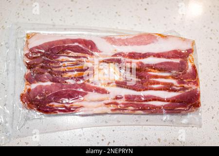 Raw uncured bacon meat vacuum sealed packaged in plastic closeup with fat and meat from above view Stock Photo