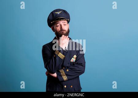 Pensive confused airline pilot in uniform questioning, making decision ...