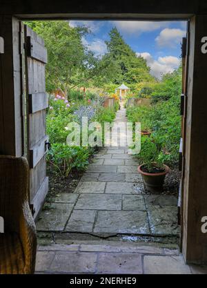 A view through an old wooden doorway at Wollerton Old Hall Gardens garden Wollerton Market Drayton Shropshire England UK Stock Photo