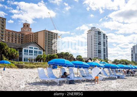 Naples, USA - December 28, 2021: Vanderbilt beach in Florida southwest with Ritz-Carlton hotel resort spa and beach chairs with umbrellas view Stock Photo