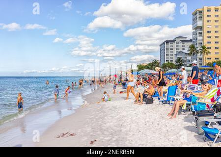 Naples, USA - December 28, 2021: Vanderbilt beach in Florida southwest gulf of mexico coast water with many people crowd sitting on chairs white sand Stock Photo