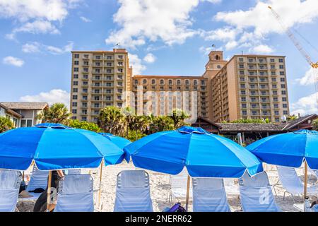 Naples, USA - December 28, 2021: Vanderbilt beach in Florida southwest with Ritz-Carlton hotel resort building exterior and beach chairs with umbrella Stock Photo