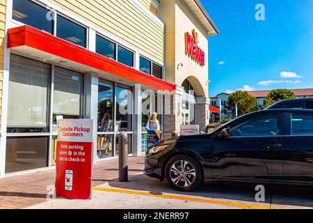 Naples, USA - January 12, 2022: Wawa gas station store exterior with sign for curbside pickup in Naples, Florida on Livingston road with cars in parki Stock Photo