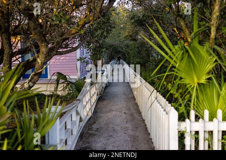 Man walking on narrow pedestrian path alley in Santa Rosa Beach, Seaside Florida by colorful pink wooden house rental property Stock Photo