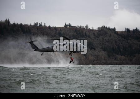 304th Rescue Squadron pararescuemen ascend a rope ladder connected to a 305th RQS HH-60G Pave Hawk helicopter during a combat search and rescue training scenario in the Columbia River Gorge, near Corbett, Oregon, Jan. 12, 2023. The two 943d Rescue Group, Davis-Monthan Air Force Base, Arizona, units carried out various rescue scenarios, ensuring Airmen are able to perform search and rescue operations in a variety of conditions and environments. (U.S. Air National Guard photo by Master Sgt. Steph Sawyer) Stock Photo