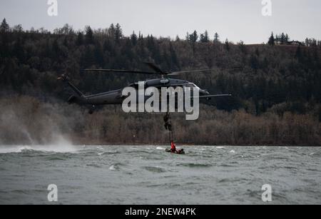 304th Rescue Squadron pararescuemen ascend a rope ladder connected to an HH-60G Pave Hawk operated by the 305th Rescue Squadron, during a rescue training scenario in the Columbia River Gorge, near Corbett, Ore., January 12, 2023. The two 943d Rescue Group, Davis-Monthan Air Force Base, Arizona, units carried out various rescue scenarios, ensuring Airmen are able to perform search and rescue operations in a variety of conditions and environments. (U.S. Air National Guard photo by Master Sgt. Steph Sawyer) Stock Photo