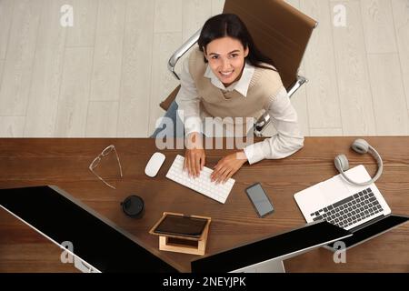 Happy programmer working at desk in office, top view Stock Photo