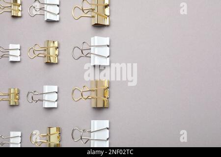Binder clips on grey background, flat lay. Space for text Stock Photo
