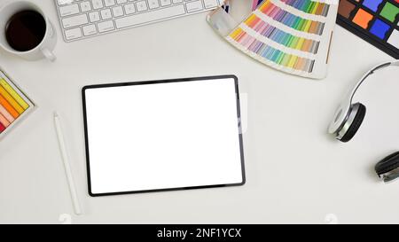 Top view of a modern minimal white graphic designer office desk with keyboard, headphones, color palette, color checker, stylus pen and digital tablet Stock Photo