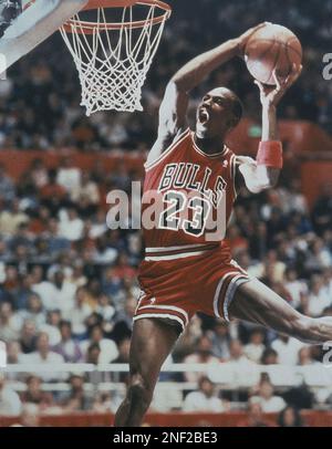 Michael Jordan of the Chicago Bulls slam dunks the ball while Utah Jazz  center Greg Ostertag, background, looks on during the first period  Saturday, Nov. 23, 1996 in Salt Lake City. (AP