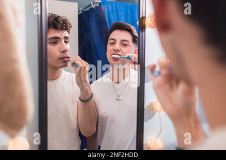 Homosexual couple brushing their teeth and looking at the mirror. Daily life of a gay couple routine Stock Photo