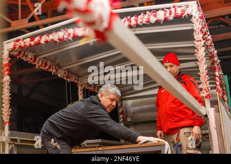 PRODUCTION - 16 February 2023, Brandenburg, Welzow: Carnivalists of the Welzower Carneval Club 1956 e.V. are putting the finishing touches to the superstructures on their float, with which they will take part in the Cottbus 'Zug der fröhlichen Leute' on Carnival Sunday. More than 50 members of the club will accompany the float under the motto 'Locker froh und heiter, beim WCC geht's immer weiter'. Starting at 1:11 p.m., more than 3,000 participants will present about 90 images from the region, from Berlin and from Saxony. Several tens of thousands of visitors are again expected to attend the l Stock Photo