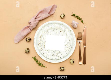 Stylish table setting with blank card and Easter eggs on color background Stock Photo
