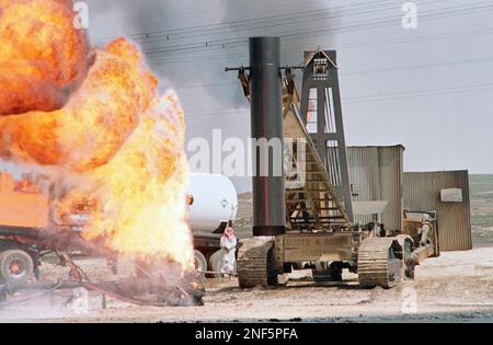 A venturi tube on the end of a boom maneuvered by a Boots and Coots operator on a frontend loader surrounded by tin to deflect hear maneuvers into position over a burning oilwell, Sunday, April 7, 1991 in Greater Burgan Oil Fields. (AP Photo/Roberto Borea)