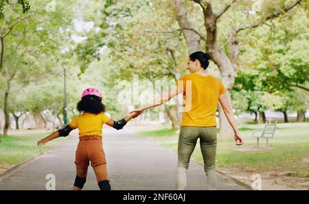 Mother, child and skating with roller skates at nature park for exercise, balance and freedom. Woman and black girl kid or family outdoor to play with Stock Photo