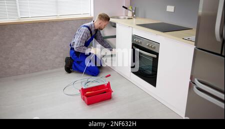 Plumber Drain Cleaning Services In Kitchen. Unclog Blocked Pipe Stock Photo