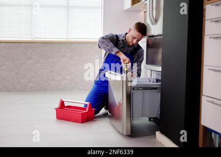 Electrician Technician Working To Repair Refrigerator Or Fridge Appliance Stock Photo