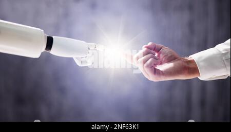 Robot Touching Human Finger Against Gray Background Stock Photo