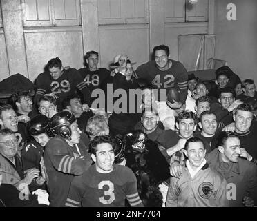 Sid Luckman, left, Chicago Bears' quarterback, gets a hug and a kiss from  teammate George McAfee, center, as Ray McLean, right, watches in the  dressing room following Chicago's defeat of the New