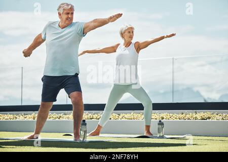 Senior couple, yoga and warrior pose in meditation by countryside for healthy spiritual wellness in nature. Elderly woman and man yogi meditating for Stock Photo