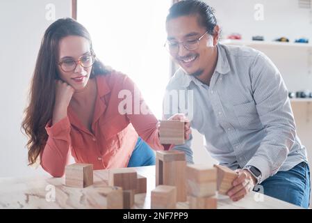 Encouraging innovation through a collaborative work culture. a young businessman and businesswoman having a meeting with building blocks in a modern Stock Photo