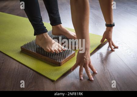 A woman practicing yoga, standing on a sadhu board with nails, doing health promotion Stock Photo