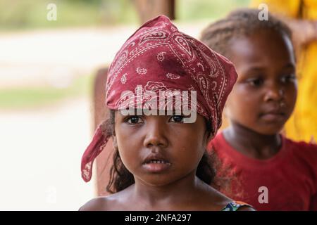 Bekopaka - Antsalova, Madagascar - November 6, 2022: Little cute Malagasy girl with a scarf on her head playing blind woman in Bekopaka village, Melak Stock Photo