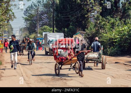Antsirabe, Madagascar - November 10. 2022: Traditional rickshaw bicycle with Malagasy people on the street of Antsirabe, one of the ways to earn money Stock Photo
