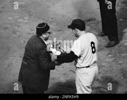 Yogi Berra, New York Yankee catcher, strides for the dugout accompanied by  trainer Gus Mauch, after being hurt in the third inning of game against the  Cleveland Indians on June 5, 1957