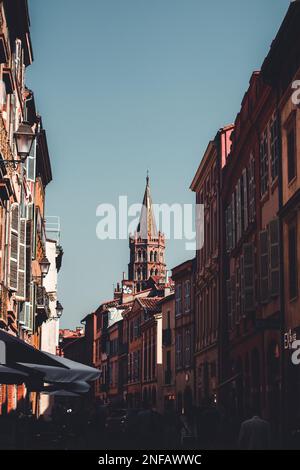 A vertical shot of the tower of the basilica St Sernin in Toulouse and a crowded street Stock Photo