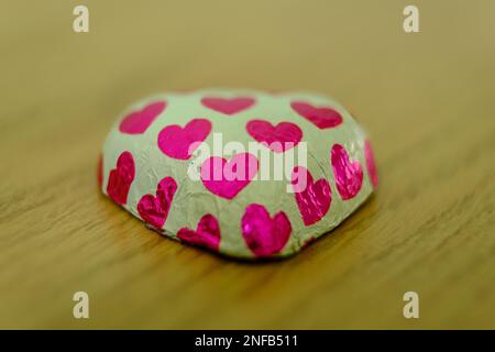 Heart-shaped chocolate candies in shiny paper with red hearts Stock Photo