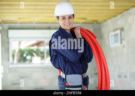 woman in dungarees carrying plastic pipes Stock Photo