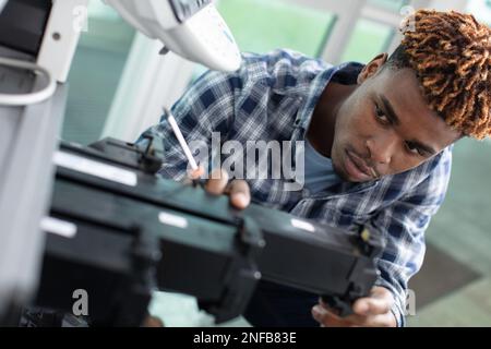 man technician trying to repair the office printer at work Stock Photo