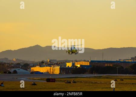 Emergency helicopter, firefighters, with the last hours of the sunset sun performing the maneuvers to land on the runway of the Sabadell airport with Stock Photo