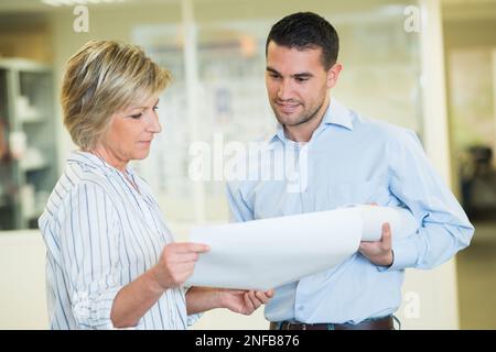mature woman showing papers to male colleague in office Stock Photo